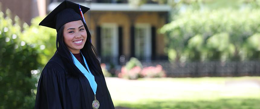 Female student in graduation cap and gown smiling