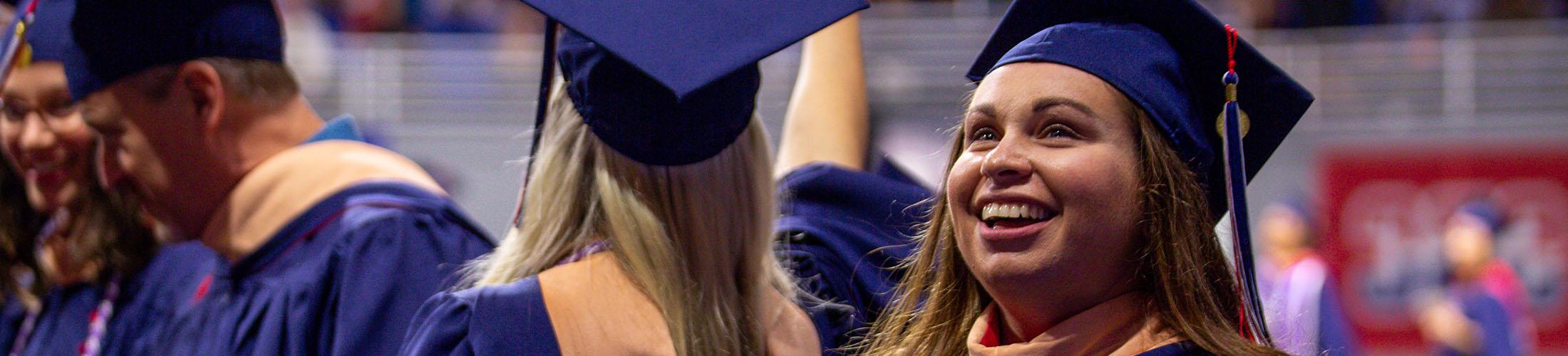 毕业典礼上的女学生头戴礼帽，身穿长袍，抬头微笑.